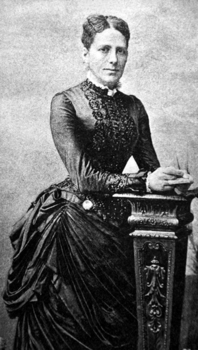 Viktoriánus korabeli nő elegáns ruhában, díszes oszlop mellett állva