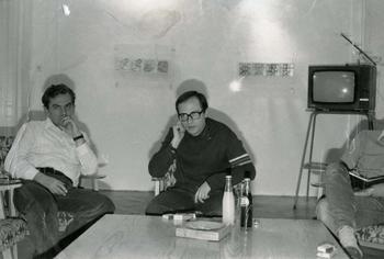Vintage Living Room Scene with TV and Drinks A vintage black and white photo of a living room with a TV, drinks, and cigarettes on a table.
