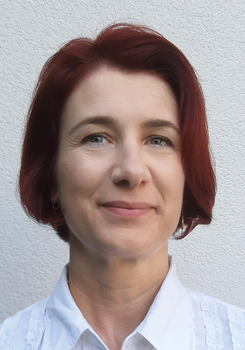 Vörös hajú nő fehér ingben, háttérben világos fal