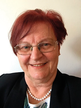 Vörös hajú személy gyöngysorral és fekete zakóban Egy személy vörös hajjal, gyöngysort viselve, fekete zakóban.